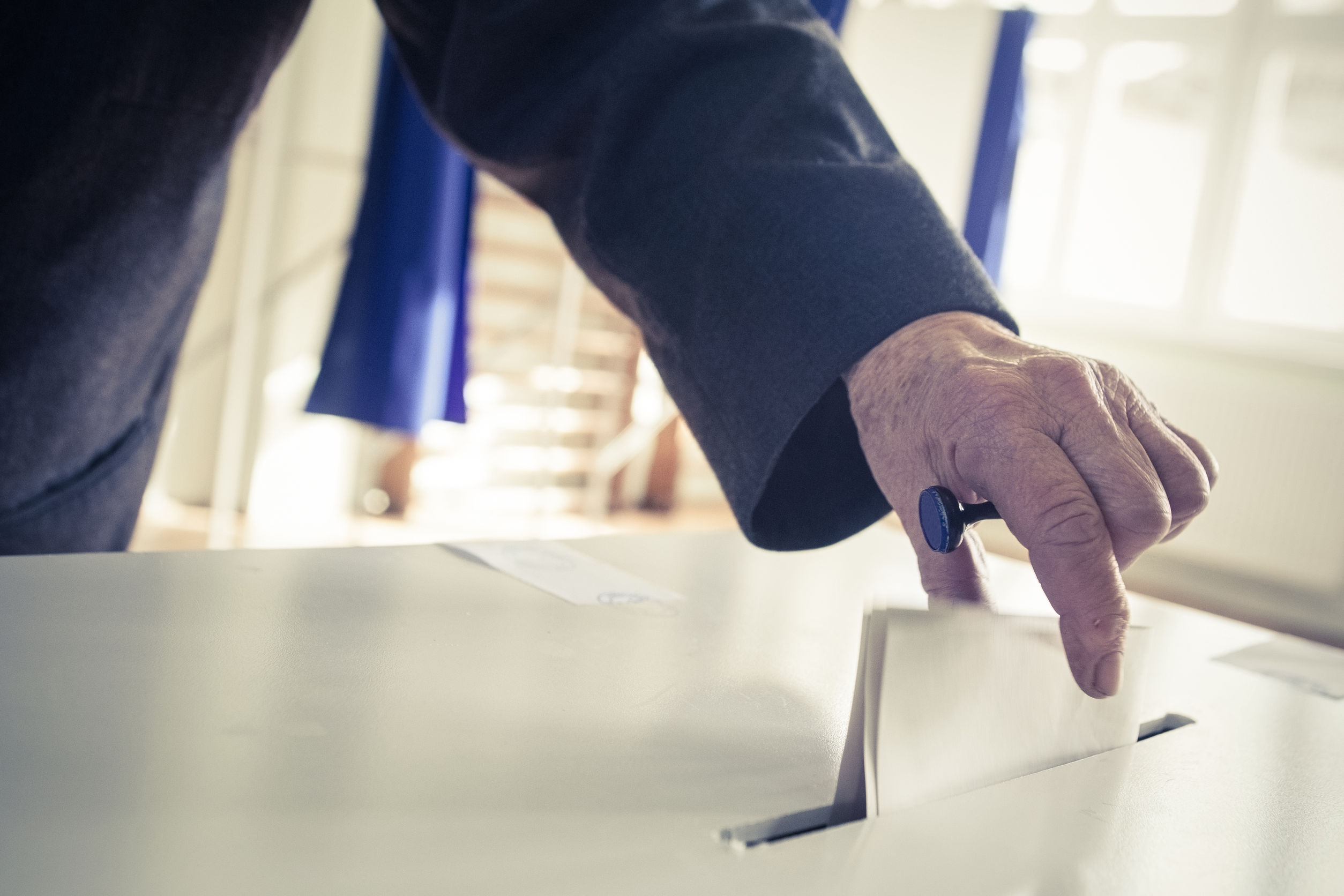 34829319 - hand of a person casting a ballot at a polling station during voting.