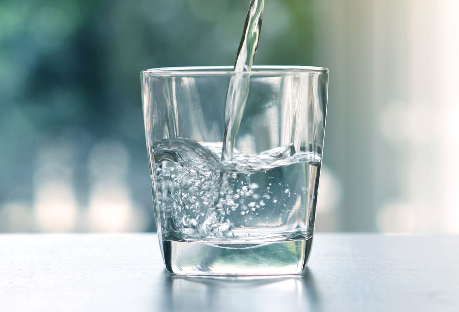 Close up pouring purified fresh drink water from the bottle on table in living room